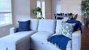 A modern living room with a sectional sofa, a dining area, and a kitchen in the background. - Backyard Sanctuary with 4 Bedrooms House (Plano)
