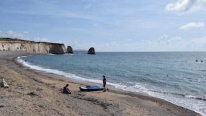 A beach with a rocky cliff, calm sea, and a few people. - 2 bedroom accommodation in Freshwater (Freshwater)