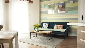 A living room with a sofa, a coffee table with a vase, and a striped wall.