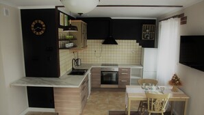 A compact kitchen with a built-in oven, a sink, and a dining area with a table and chairs.