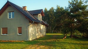 A two-story house with a sloped roof, a chimney, and a small window with a shutter.
