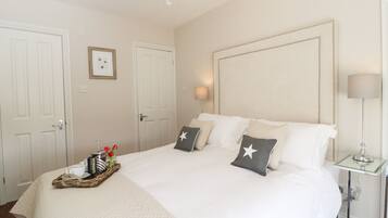 A hotel room with a large bed, two bedside tables, a chandelier, and a framed picture on the wall.