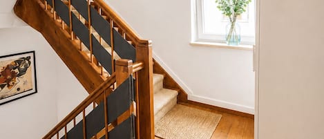 Una escalera de madera con barandal negro que lleva a una plataforma.