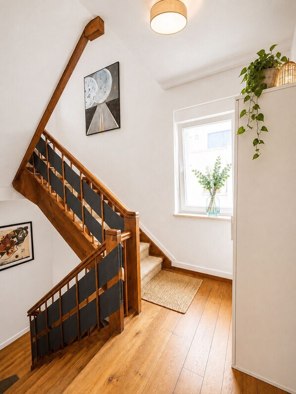 Una escalera de madera con barandal negro que lleva a una plataforma.