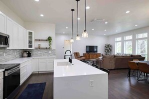 A modern kitchen with white cabinets, a central island, and pendant lighting. - Two Primary Suites, Family & Dog Friendly (McCall)