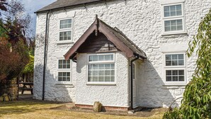 Une maison en pierre blanche avec un toit à pignon, de nombreuses fenêtres et une cheminée.