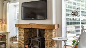 Un salon chaleureux avec une cheminée en pierre, un téléviseur à écran plat et un coin salon confortable.