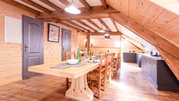 Un intérieur chaleureux en bois, comprenant un coin repas, une cuisine et une chambre à coucher située en mezzanine.