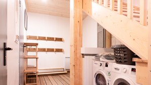 Une buanderie avec un plancher en bois, un lave-linge, un sèche-linge et un panier à linge.