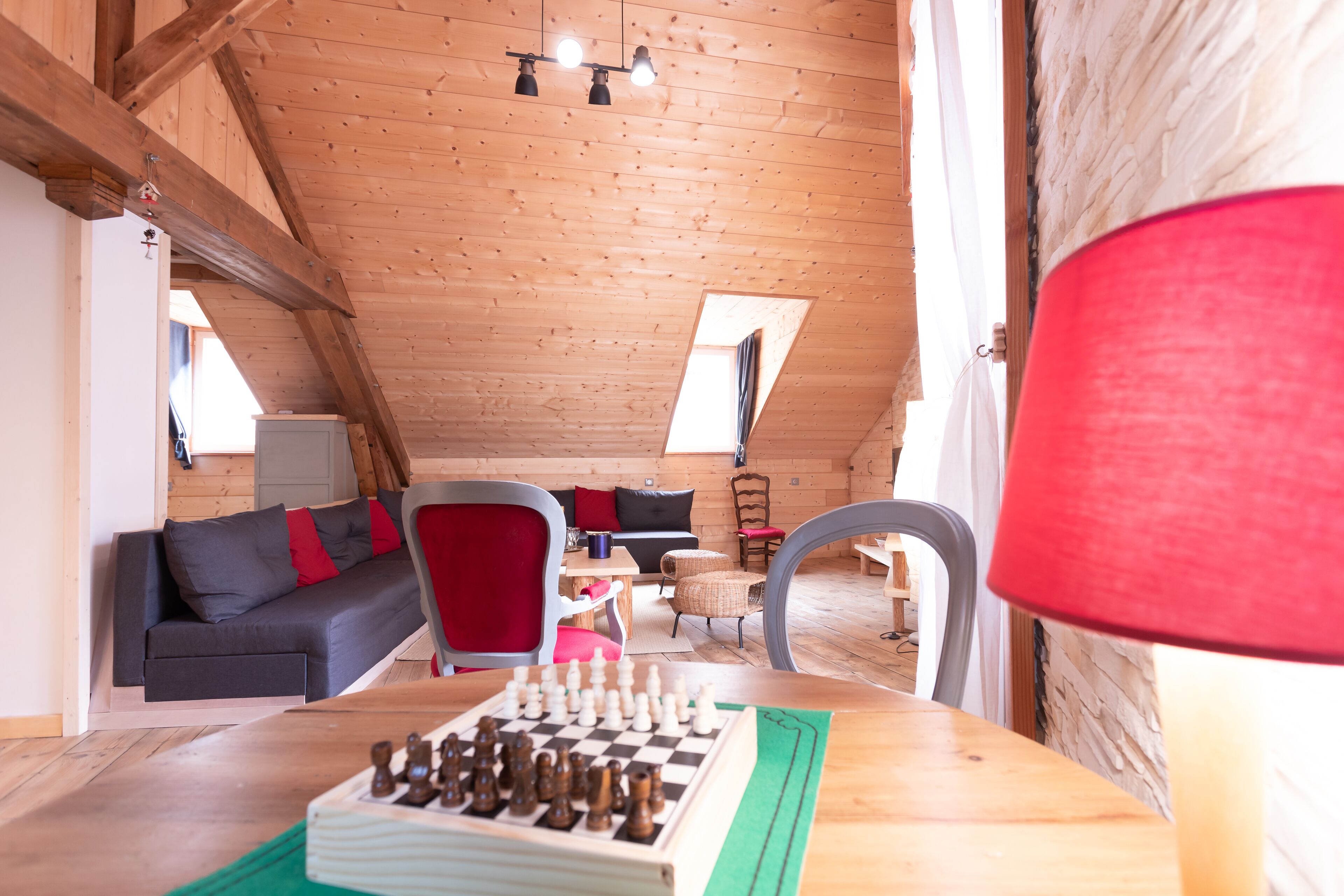 Een gezellig loft met houten plafond, een bank, een eettafel en een schaakbord.
