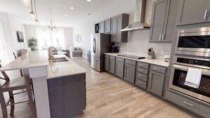 A modern kitchen with grey cabinets, stainless steel appliances, and a central island.