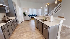 A modern kitchen with grey cabinets, a central island, and a built-in oven.