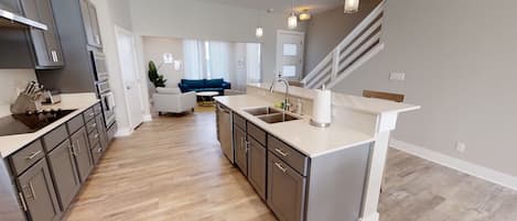 A modern kitchen with grey cabinets, a central island, and a built-in oven.