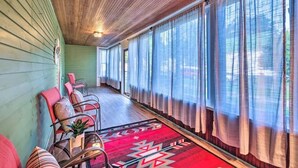 Ein Zimmer mit Holzboden, einem roten Teppich mit Muster und einer Reihe von Stühlen am Fenster.