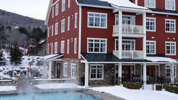 Un bâtiment rouge avec une piscine et un toit recouvert de neige.