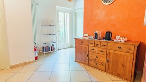 A kitchen with a wooden cabinet, a coffee maker, and a kettle on the counter.
