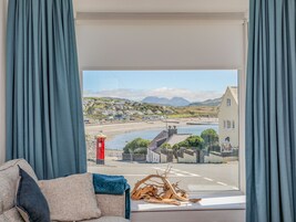 Una habitación con vistas a un pueblo costero, una cabina telefónica roja y un muro de piedra con una reja.