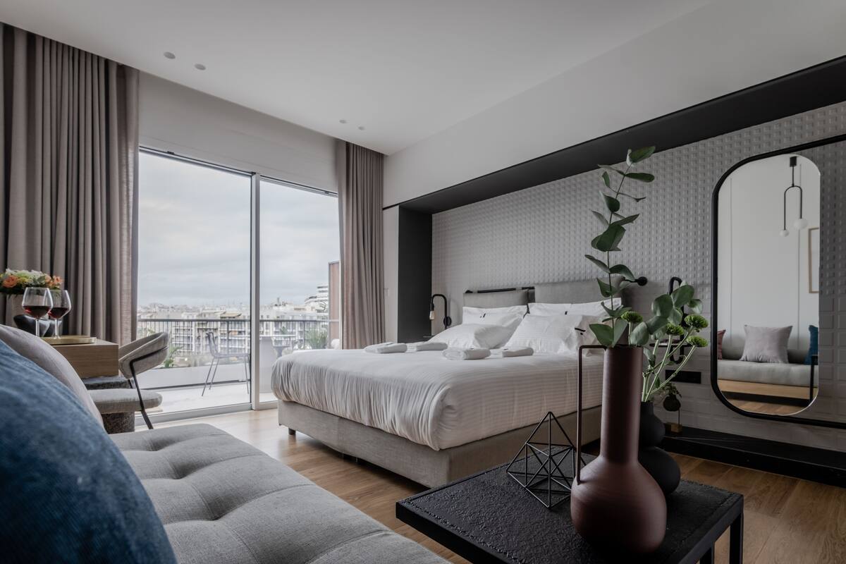Un dormitorio moderno con una cama grande, vistas a la ciudad y un balcón.