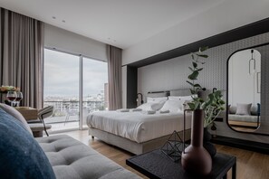 A modern bedroom with a large bed, a view of the city, and a balcony. - Athinaion Recreation Suites (Athens)