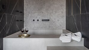 A modern bathroom with a marble vanity, a towel rack, and two glasses of red wine on a tray. - Athinaion Recreation Suites (Athens)