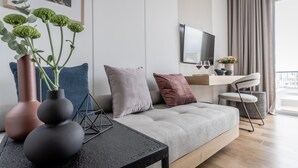A modern living room with a grey sofa, a black coffee table, and a TV mounted on the wall. - Athinaion Recreation Suites (Athens)