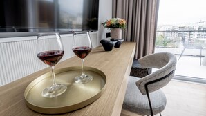 A modern living room with a TV, two wine glasses on a tray, a potted plant, and a view of the city. - Athinaion Recreation Suites (Athens)