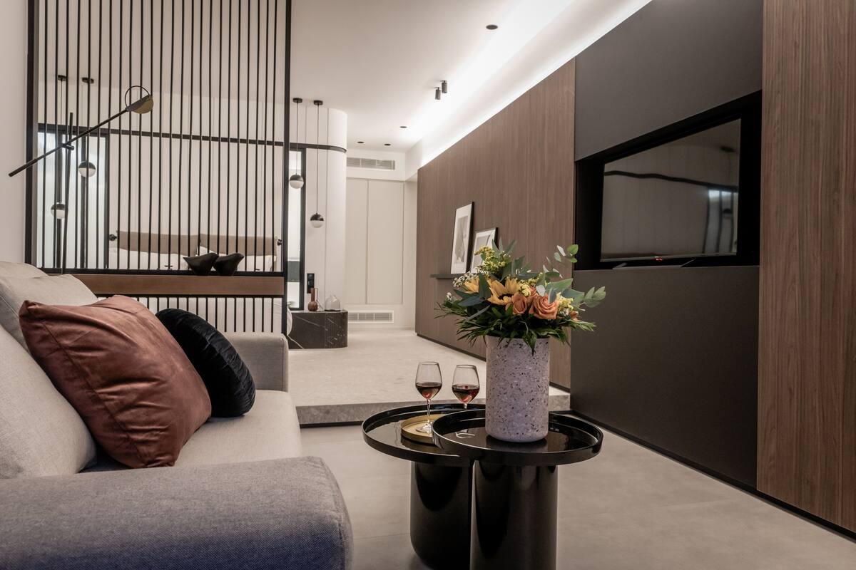 Una sala de estar moderna con un sofá, una mesa de centro con un florero, y una escalera al fondo.