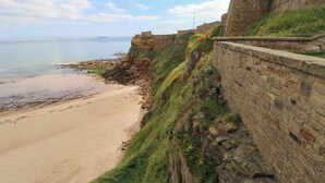 A coastal fortification with a sandy beach and a clear view of the sea.