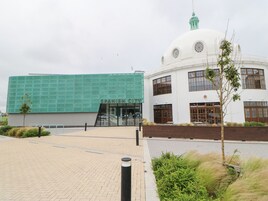 Un edificio con fachada verde y una estructura abovedada blanca.