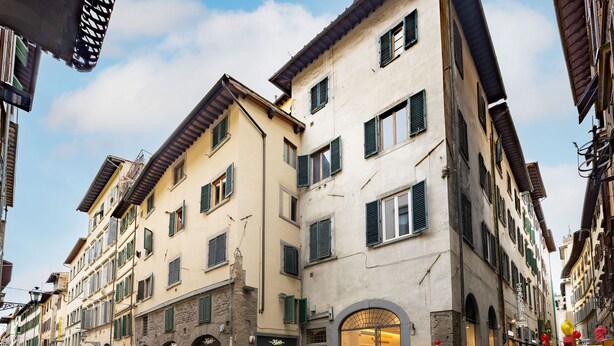 Una calle con edificios históricos, comercios y gente caminando.