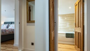 Ein Schlafzimmer mit Bett, ein Badezimmer mit Badewanne und einer Holztür.