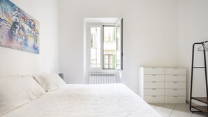 Et soveværelse med seng, radiator, et vindue og et billede på væggen.