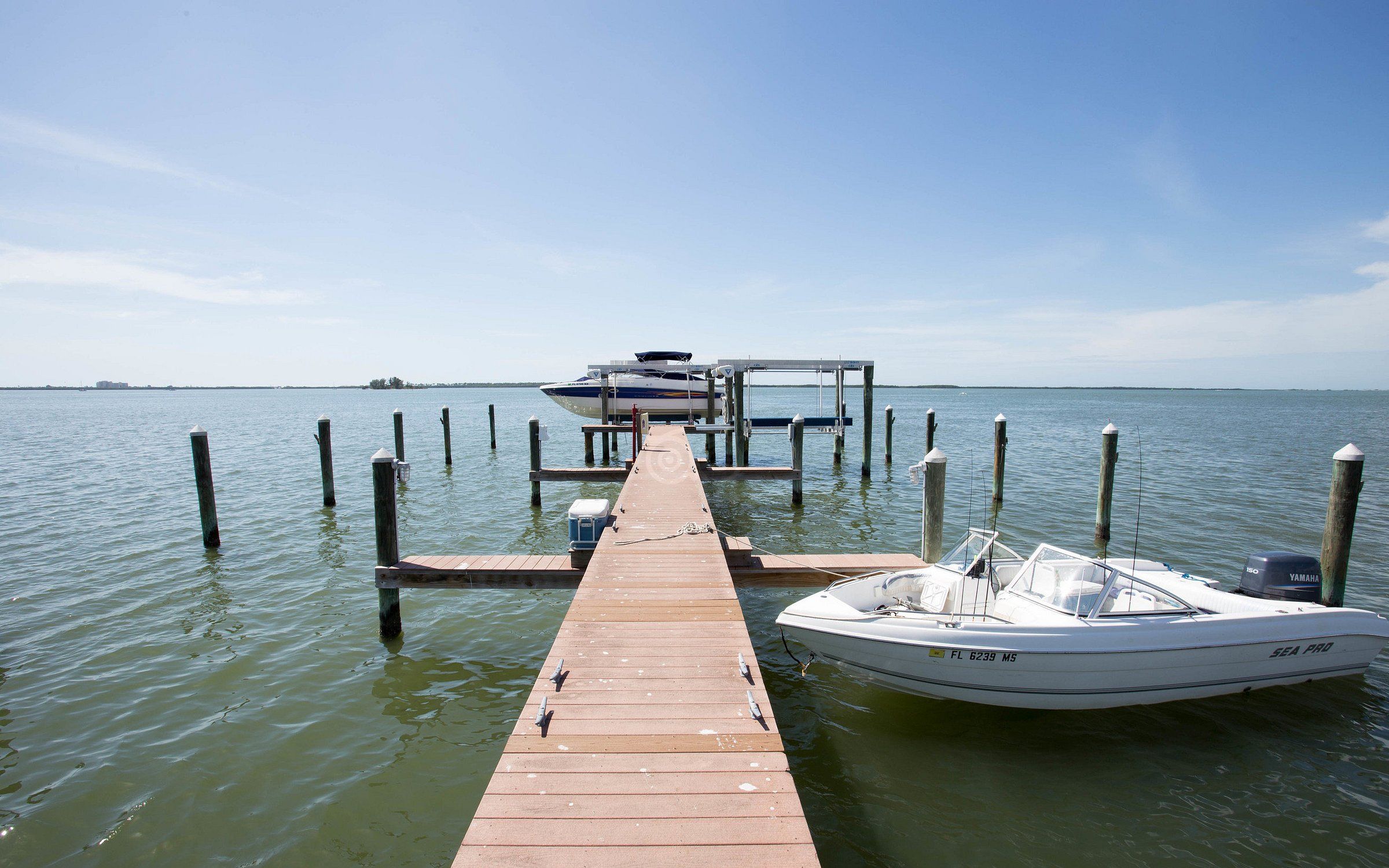 A wooden pier extending into calm water with a boat docked at the end.