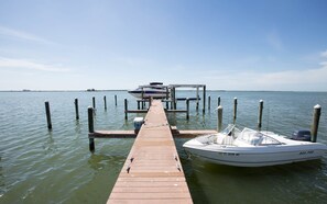 Un muelle de madera que se adentra en aguas tranquilas, con un barco amarrado al final.