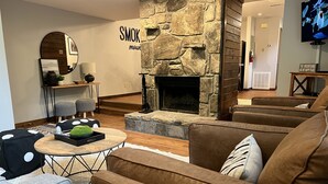 Ein gemütliches Wohnzimmer mit Kamin aus Stein, bequemen Sofas und einem Couchtisch mit Dekoration.