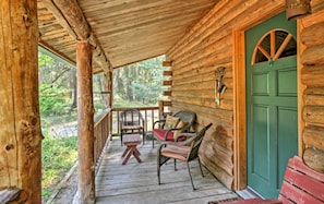 A wooden cabin with a porch, a green door, and wicker furniture.
