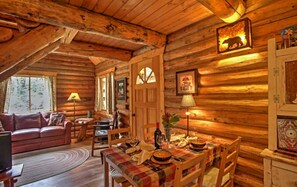 A cozy log cabin interior with a dining area, a sofa, and a fireplace.
