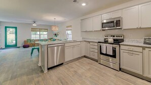 A modern kitchen with white cabinets, stainless steel appliances, and a central island.