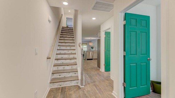 A staircase leading to a kitchen area with teal doors.