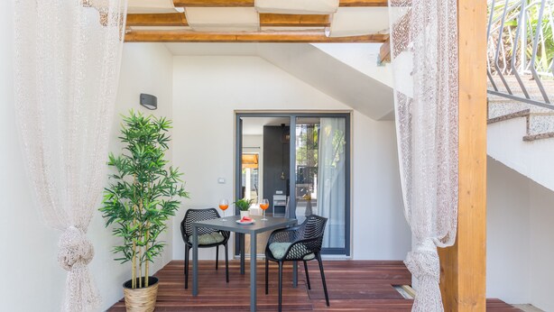 Eine Terrasse mit Tisch und Stühlen, einem Blumentopf und einer Schiebetür zu einem Innenbereich.