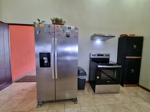 Eine kompakte Küche mit einem Edelstahl-Kühlschrank, einem eingebauten Ofen und einer Mikrowelle.