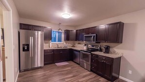 A modern kitchen with dark wood cabinets, stainless steel appliances, and a granite countertop. - Quiet & Private! 2BD w/ Laundry and Full Kitchen (Meadow Lakes)