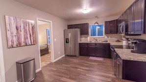 A modern kitchen with dark cabinets, stainless steel appliances, and a wooden floor. - Quiet & Private! 2BD w/ Laundry and Full Kitchen (Meadow Lakes)
