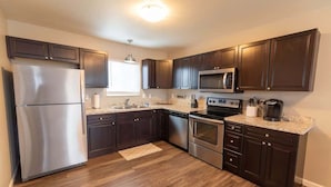 A modern kitchen with dark wooden cabinets, stainless steel appliances, and a granite countertop. - 2BR Private Suite w/ Full Kitchen & Laundry! (Meadow Lakes)