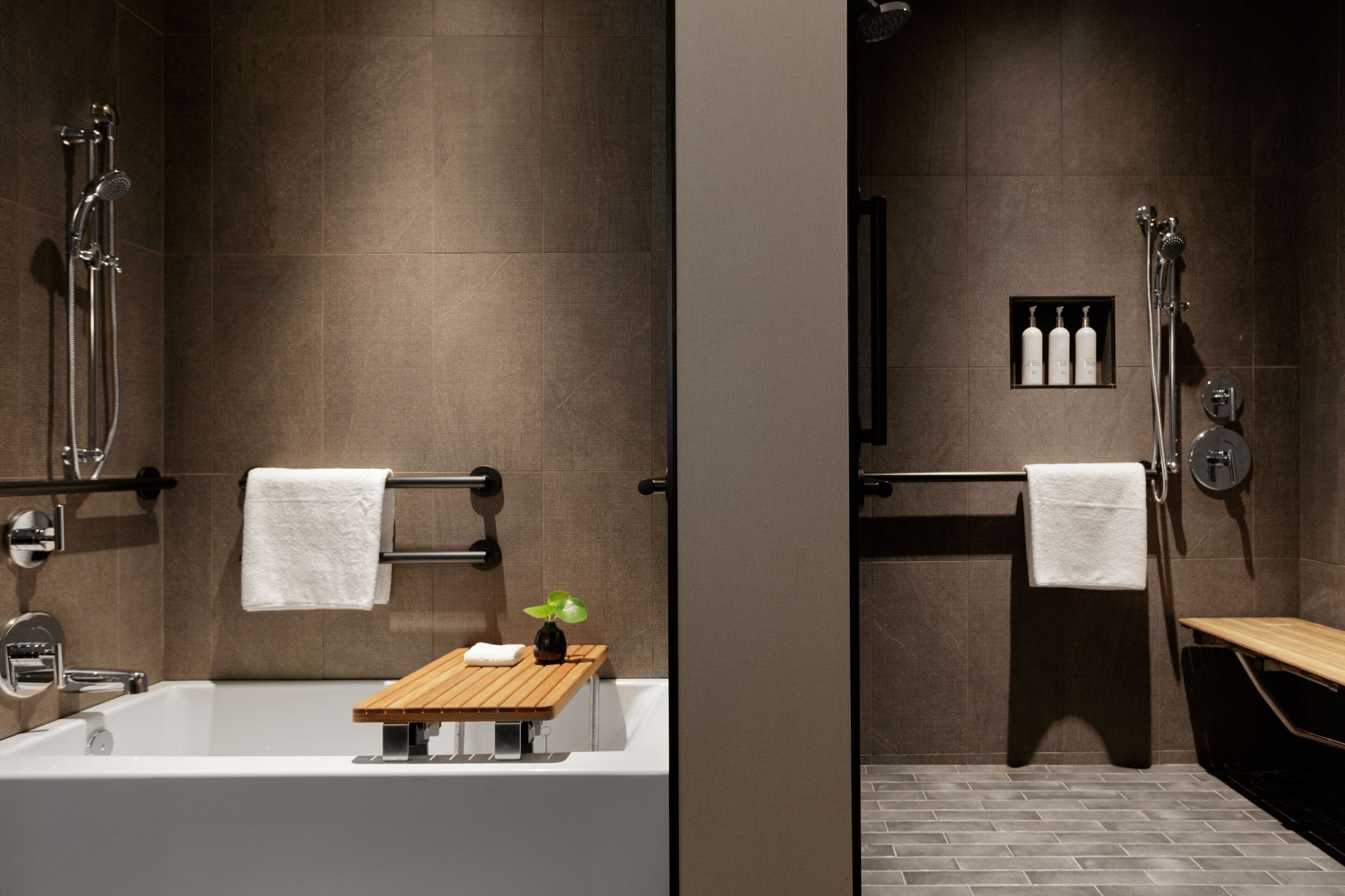 Un baño moderno con bañera, ducha y un pequeño estante de madera con una planta.
