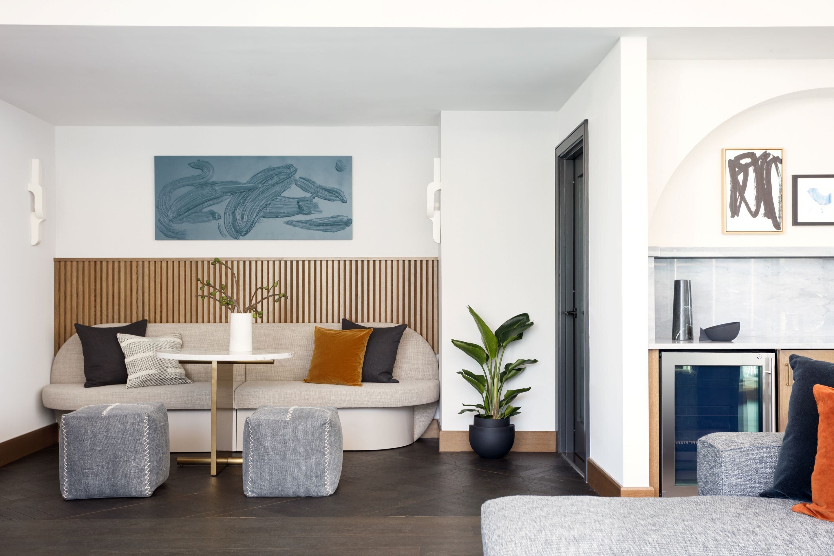 A modern living room with a sofa, ottomans, a small table, and a potted plant.
