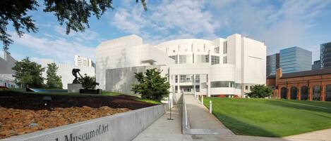 A pathway leading to the High Museum of Art with a stone wall and a grassy area.