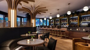 A modern bar area with round tables, black leather seating, and a bar counter with various bottles.