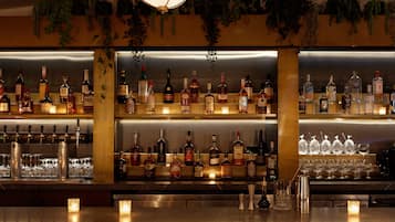 A bar area with multiple shelves of liquor bottles, glasses, and a few candles.