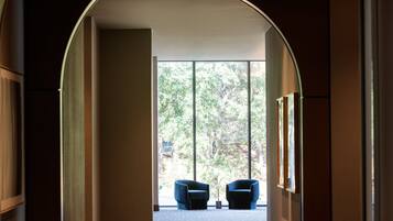 A hallway with a large arched doorway leading to a room with two blue chairs and a large window.